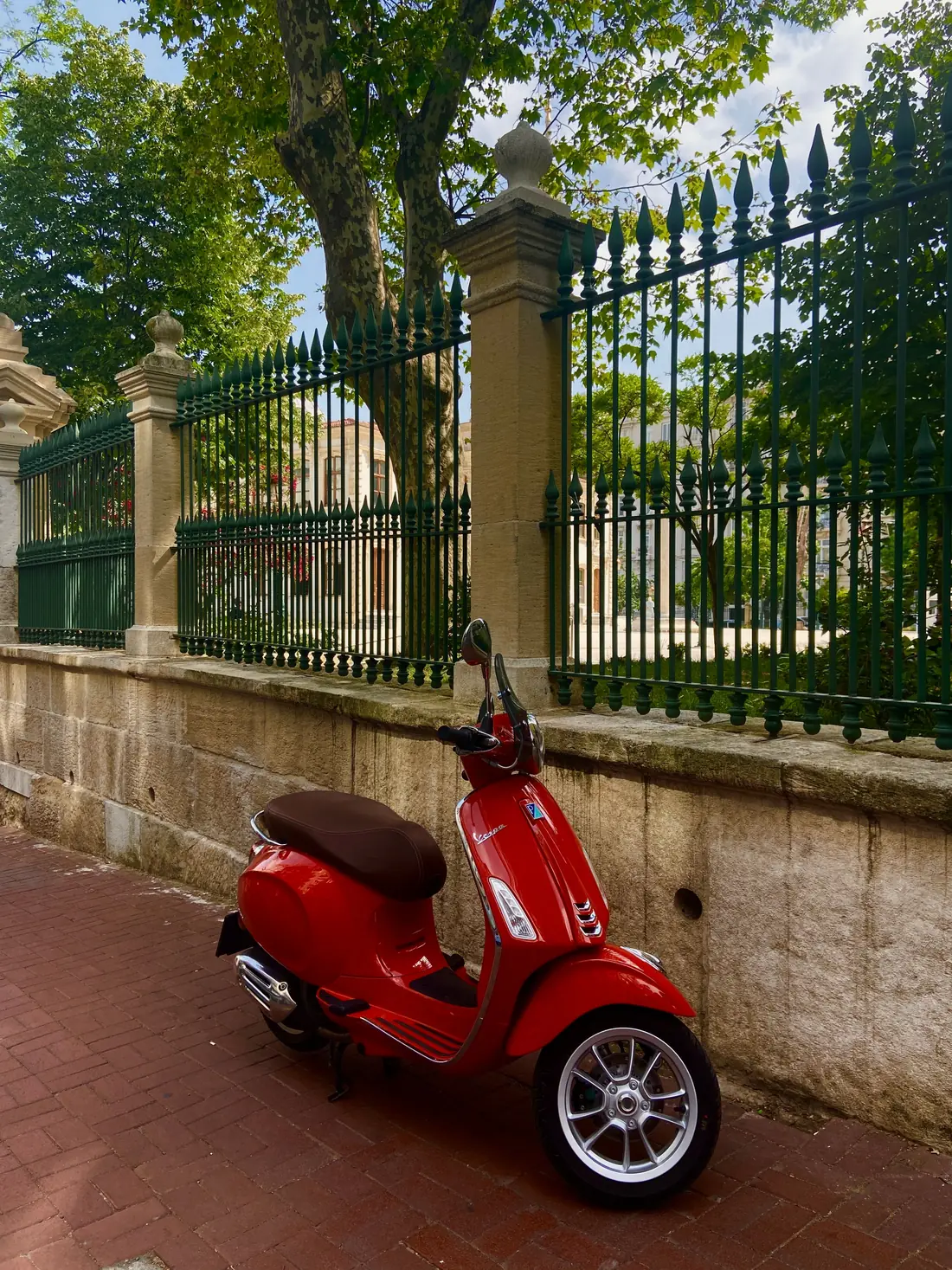Red Vespa 50 parked beside a wrought-iron fence in Zadar